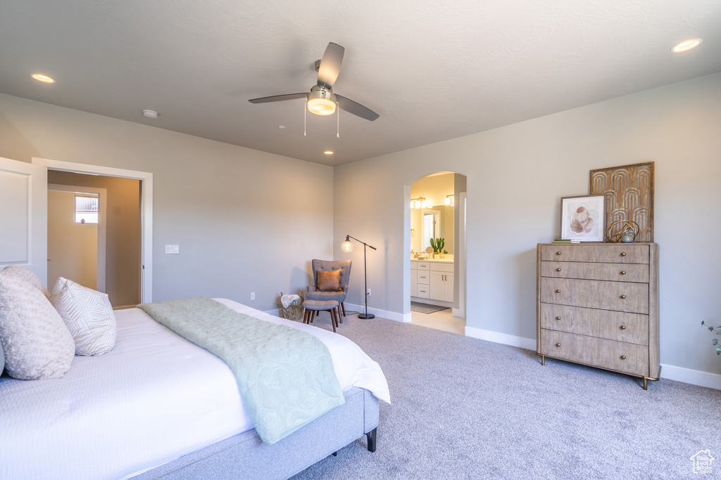 Carpeted bedroom with ensuite bath and ceiling fan