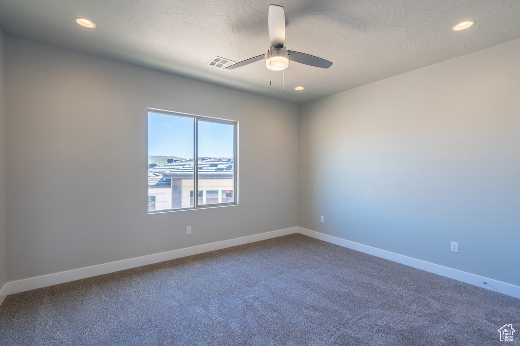 Carpeted spare room featuring ceiling fan and a textured ceiling