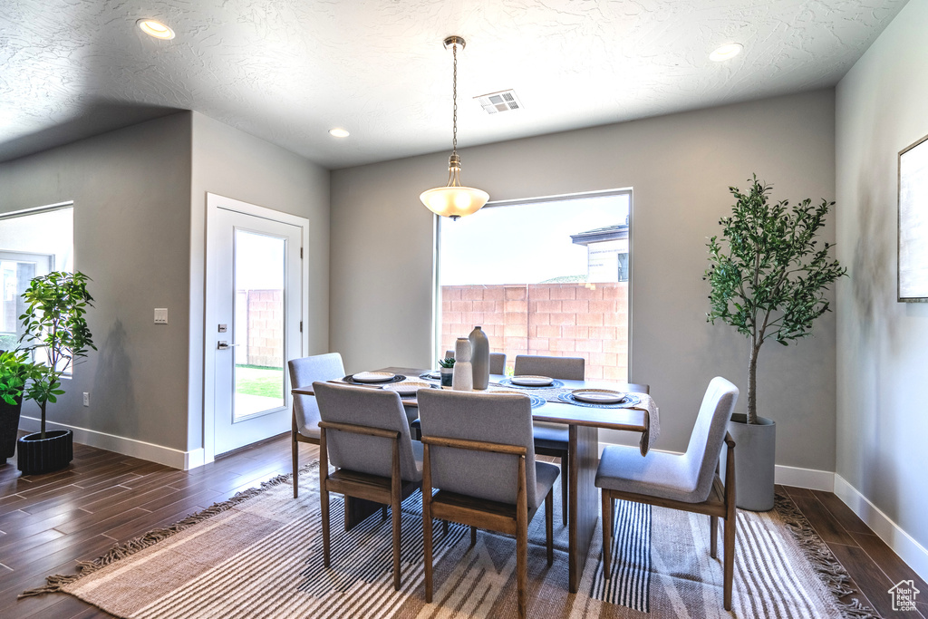 Dining room with a textured ceiling and dark wood-type flooring