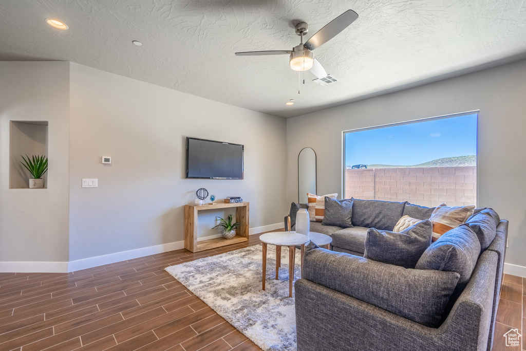 Living room featuring ceiling fan, a textured ceiling, and dark wood-type flooring
