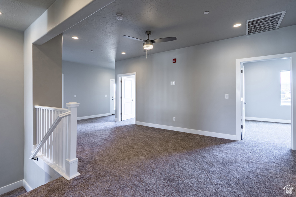 Spare room with ceiling fan, a textured ceiling, and dark colored carpet