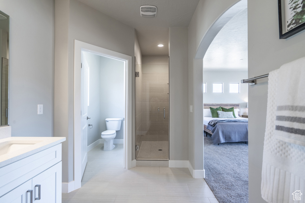 Bathroom with vanity, a shower with shower door, and toilet