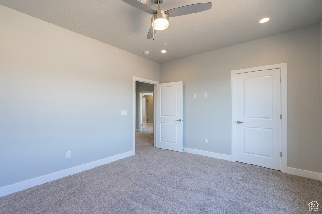 Unfurnished bedroom featuring ceiling fan and light colored carpet