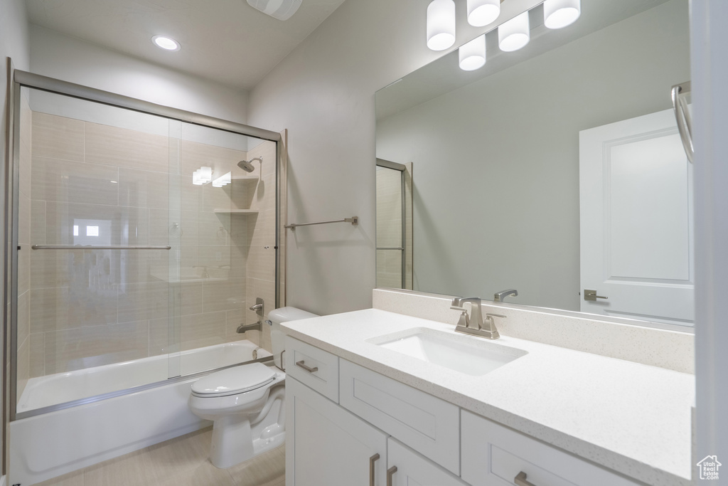 Full bathroom with shower / bath combination with glass door, vanity, and toilet