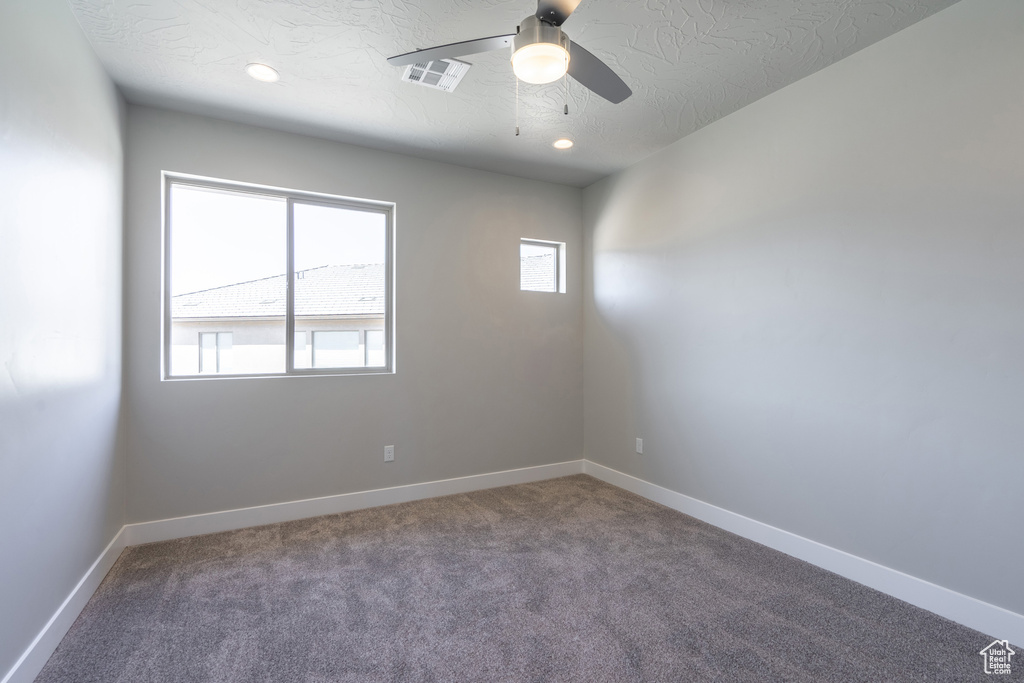 Carpeted empty room with a textured ceiling and ceiling fan