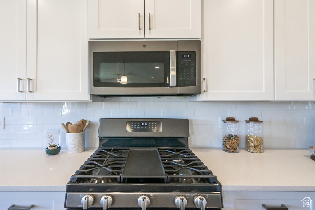 Kitchen featuring white cabinetry and appliances with stainless steel finishes