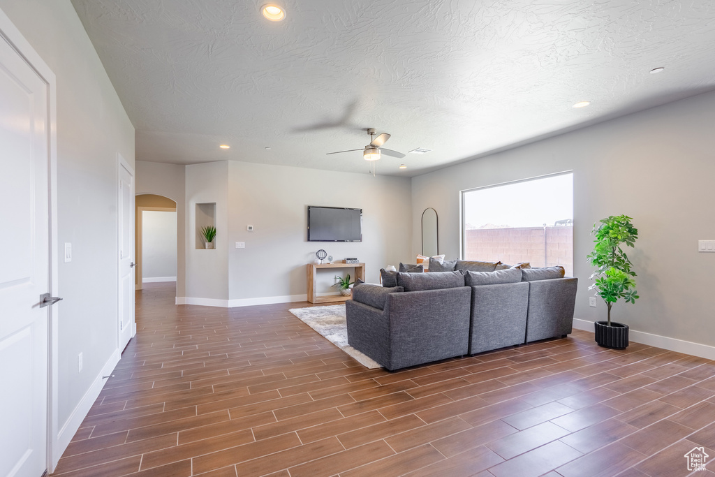 Living room featuring ceiling fan, a textured ceiling, and dark hardwood / wood-style floors