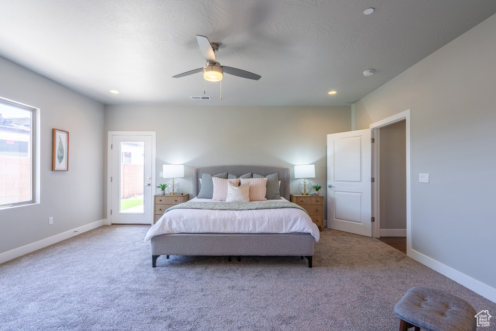 Carpeted bedroom featuring multiple windows, access to outside, and ceiling fan