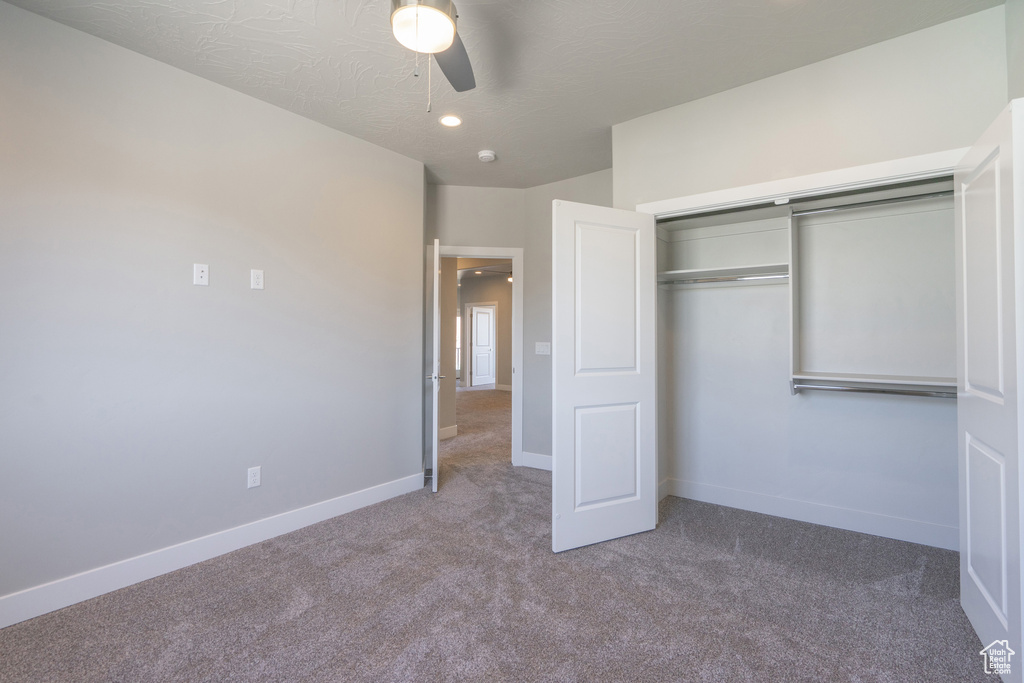Unfurnished bedroom featuring carpet flooring, a closet, ceiling fan, and a textured ceiling