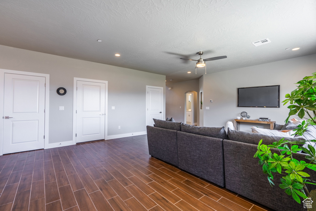 Living room featuring a textured ceiling, dark hardwood / wood-style flooring, and ceiling fan