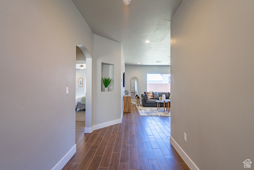 Hall featuring a textured ceiling and dark hardwood / wood-style floors