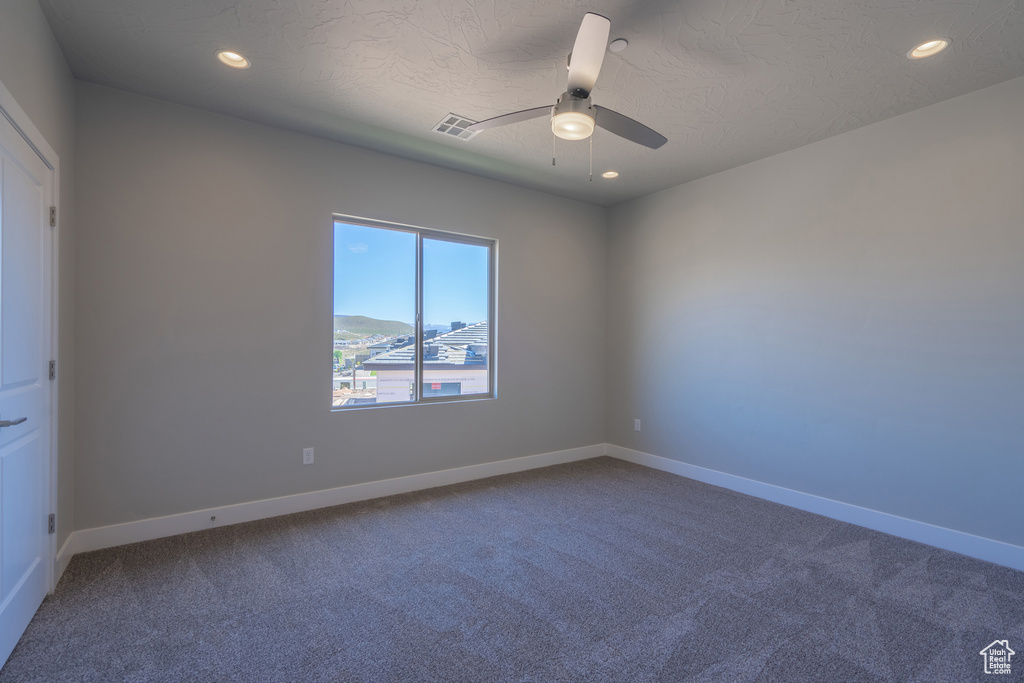 Carpeted spare room with a mountain view, a textured ceiling, and ceiling fan