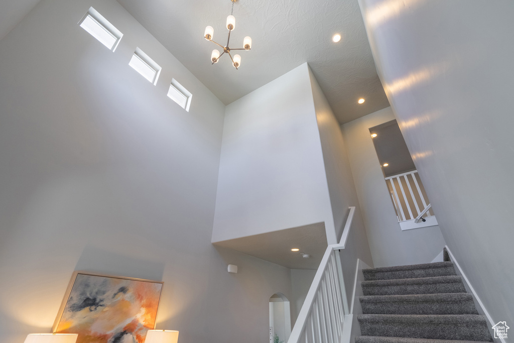 Stairs featuring an inviting chandelier and high vaulted ceiling