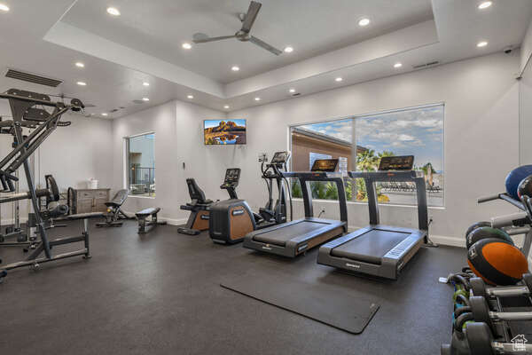 Workout area featuring a tray ceiling and ceiling fan