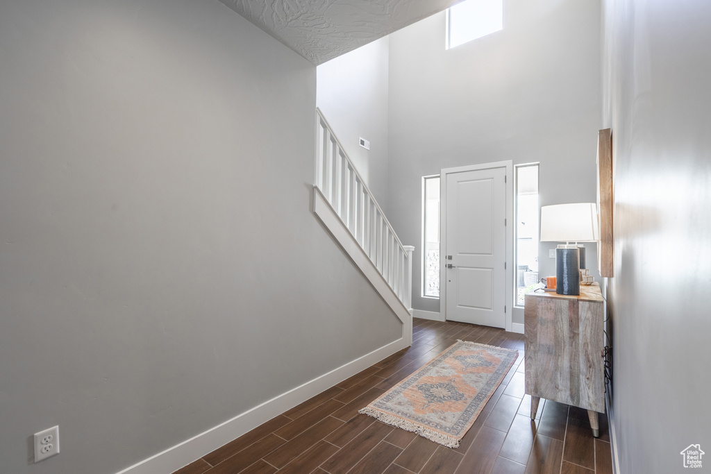 Foyer entrance with a towering ceiling and dark hardwood / wood-style flooring