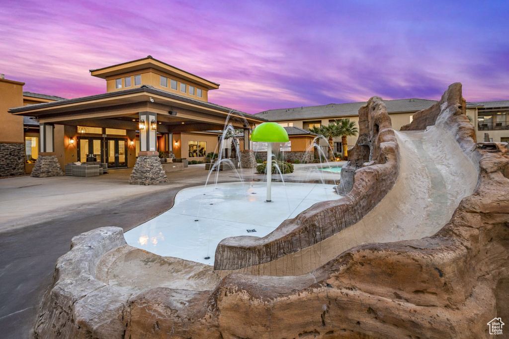 Pool at dusk with pool water feature and a patio area