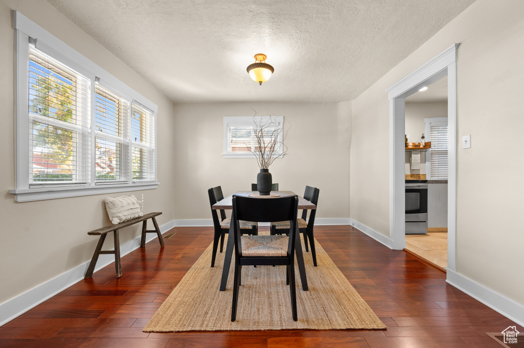 Dining space with a textured ceiling and dark hardwood / wood-style flooring