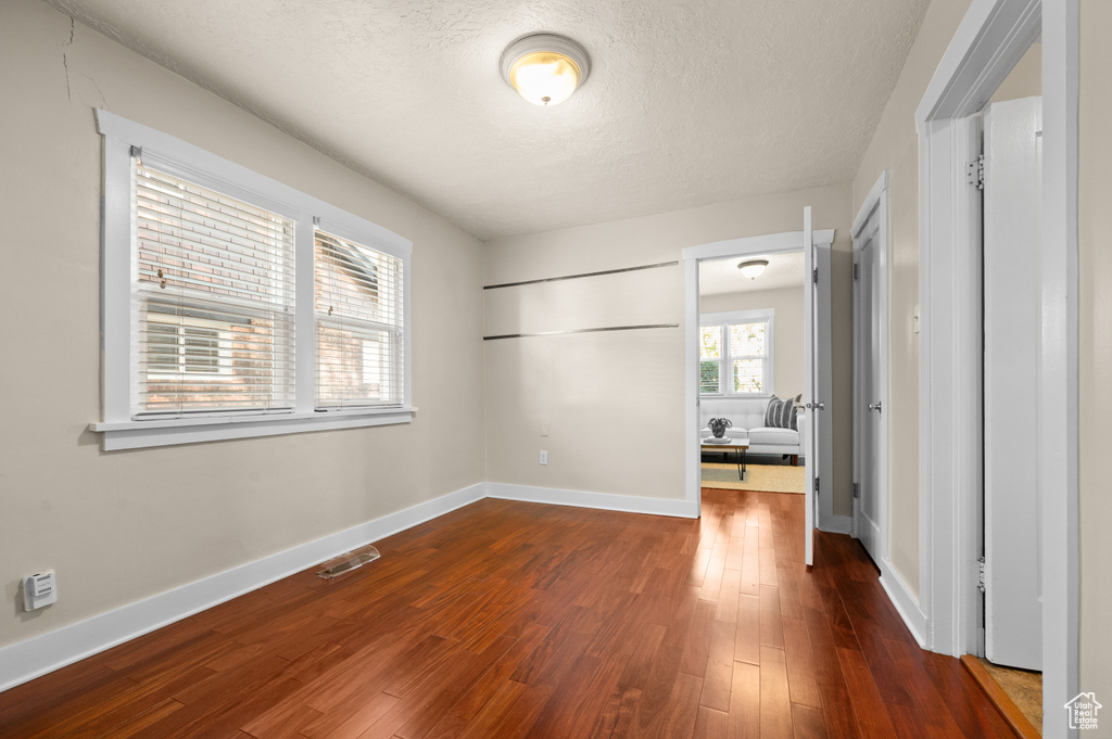 Unfurnished bedroom featuring a textured ceiling and dark wood-type flooring