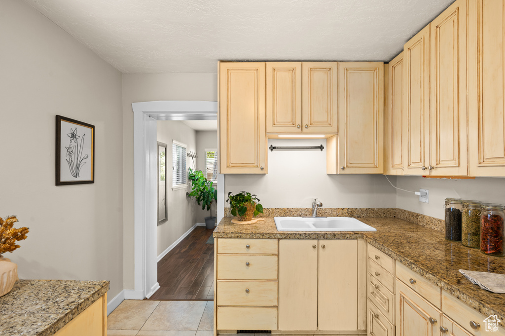 Kitchen with light brown cabinetry, light stone countertops, light hardwood / wood-style floors, and sink