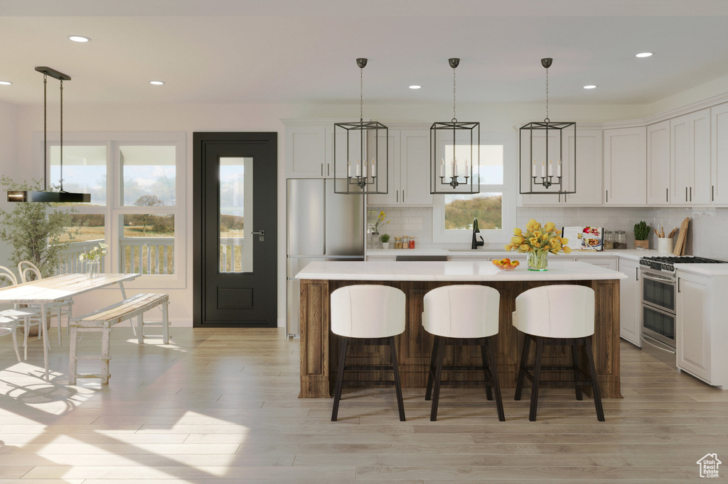 Kitchen with decorative light fixtures, backsplash, a center island, stainless steel range, and light wood-type flooring