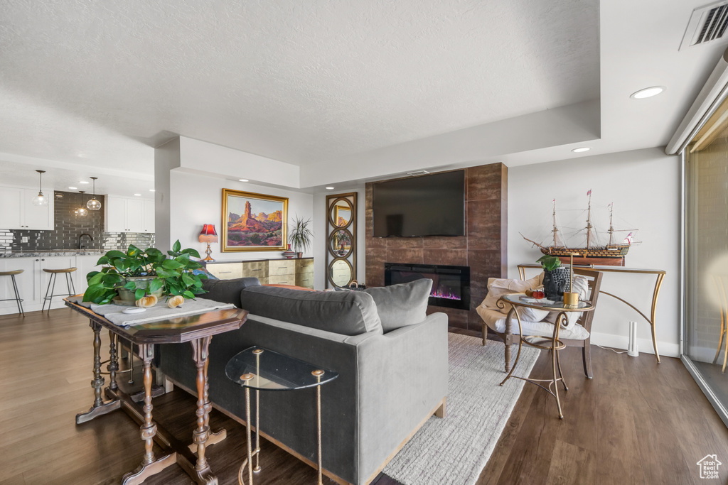 Living room featuring a textured ceiling, a fireplace, a tray ceiling, and dark hardwood / wood-style floors