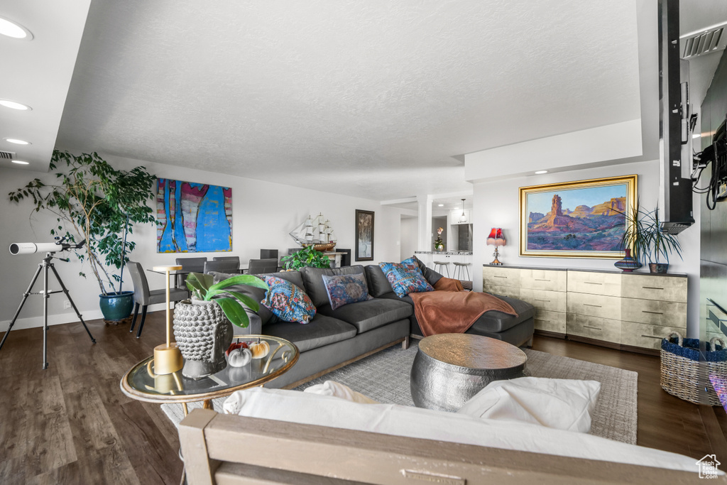 Living room with a textured ceiling and dark wood-type flooring