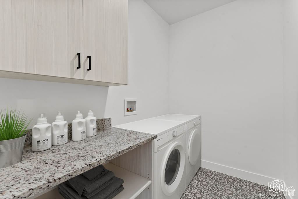 Laundry area with washer hookup, cabinets, and light tile patterned floors