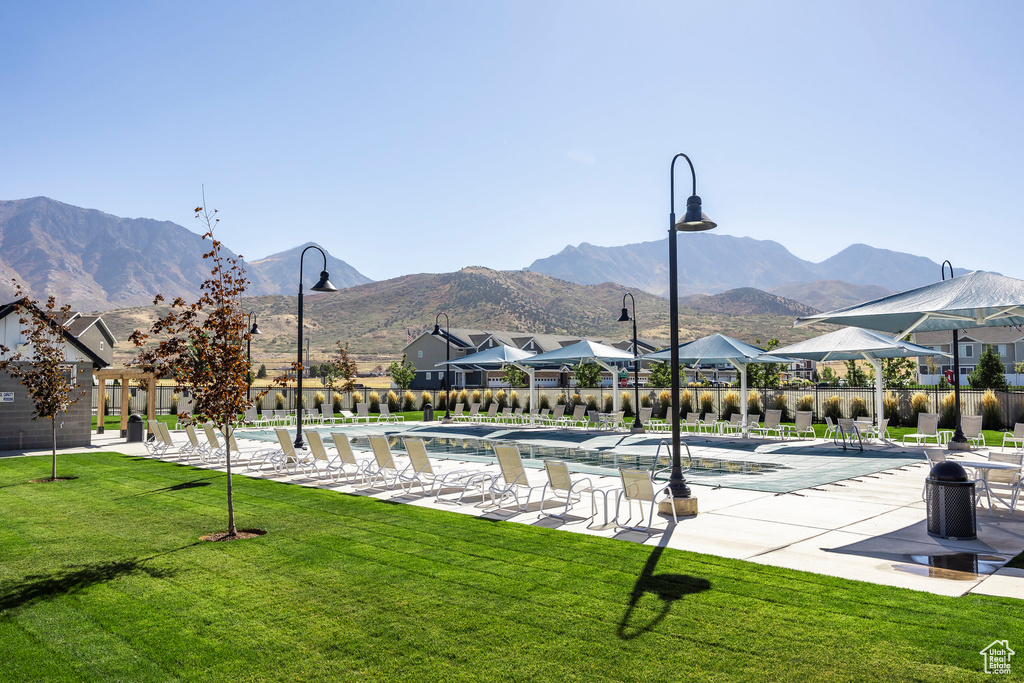 View of home's community with a lawn, a pool, a mountain view, and a patio area