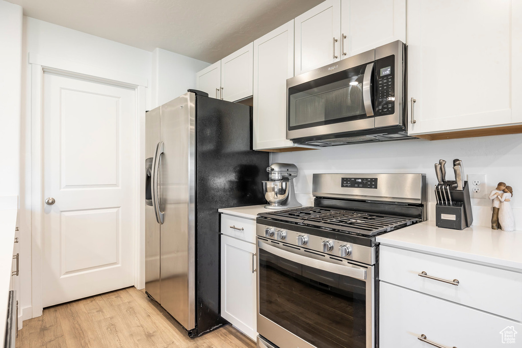 Kitchen featuring white cabinets, light hardwood / wood-style floors, and appliances with stainless steel finishes