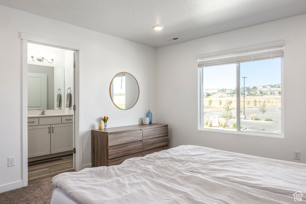 Bedroom with connected bathroom, sink, and dark colored carpet