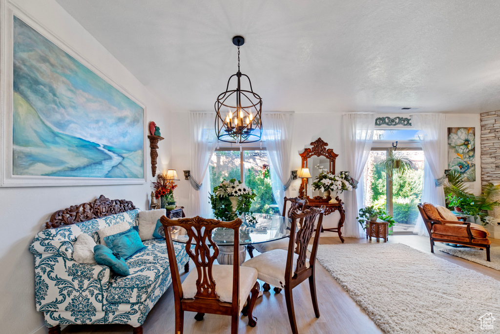 Dining area with light wood-type flooring and an inviting chandelier