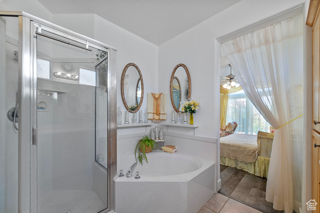 Bathroom featuring shower with separate bathtub, ceiling fan, and tile patterned floors