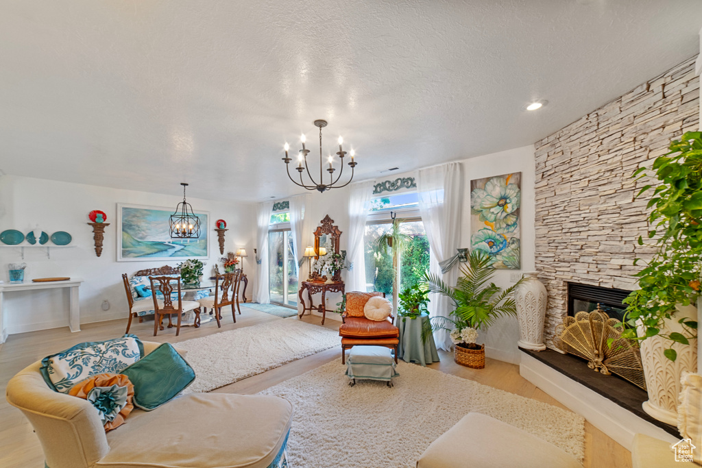 Living room with light hardwood / wood-style flooring, an inviting chandelier, a textured ceiling, and a fireplace