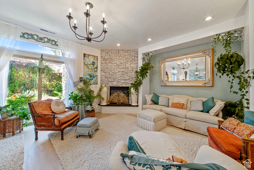 Living room featuring light wood-type flooring, a chandelier, and a fireplace