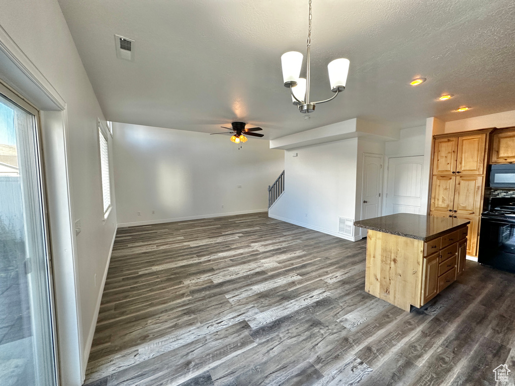 Kitchen with a kitchen island, black appliances, ceiling fan with notable chandelier, and dark hardwood / wood-style floors