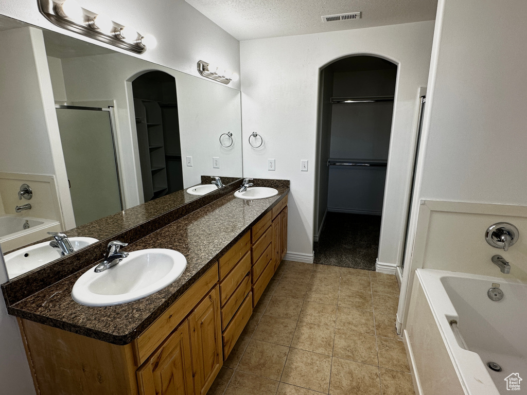 Bathroom featuring a textured ceiling, tile patterned flooring, vanity, and separate shower and tub