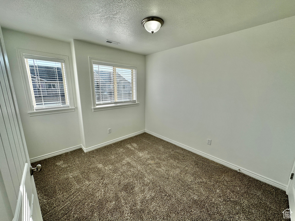 Carpeted empty room featuring a textured ceiling