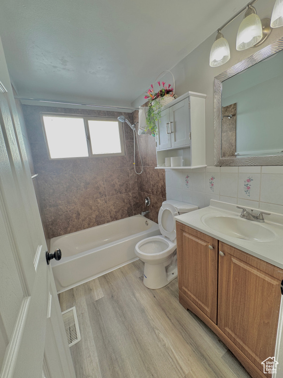 Full bathroom with tasteful backsplash, vanity, toilet, and tiled shower / bath