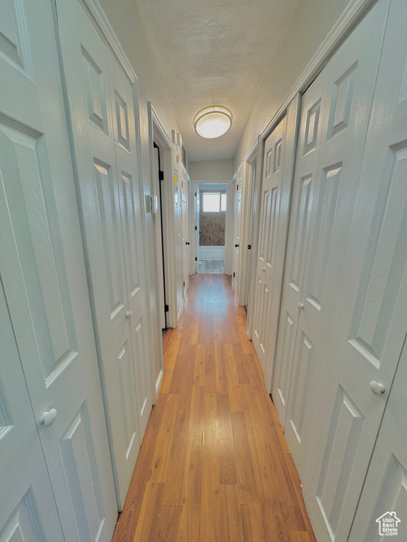 Corridor with light hardwood / wood-style floors and a textured ceiling