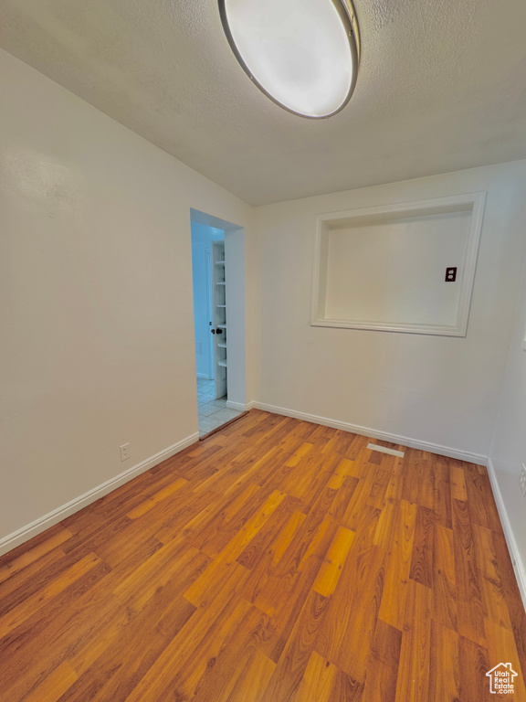 Spare room featuring a textured ceiling and light hardwood / wood-style flooring