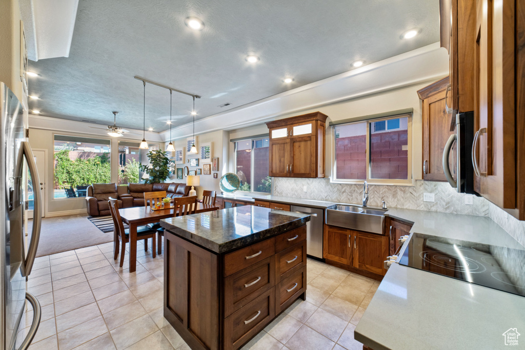 Kitchen featuring a kitchen island, light tile patterned floors, pendant lighting, stainless steel appliances, and sink