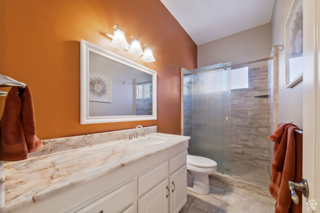 Bathroom with vanity, tile patterned flooring, toilet, and a shower with door