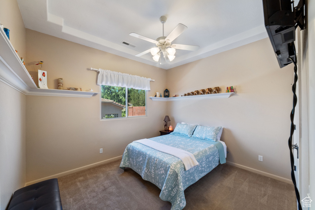 Bedroom featuring carpet flooring, a tray ceiling, and ceiling fan