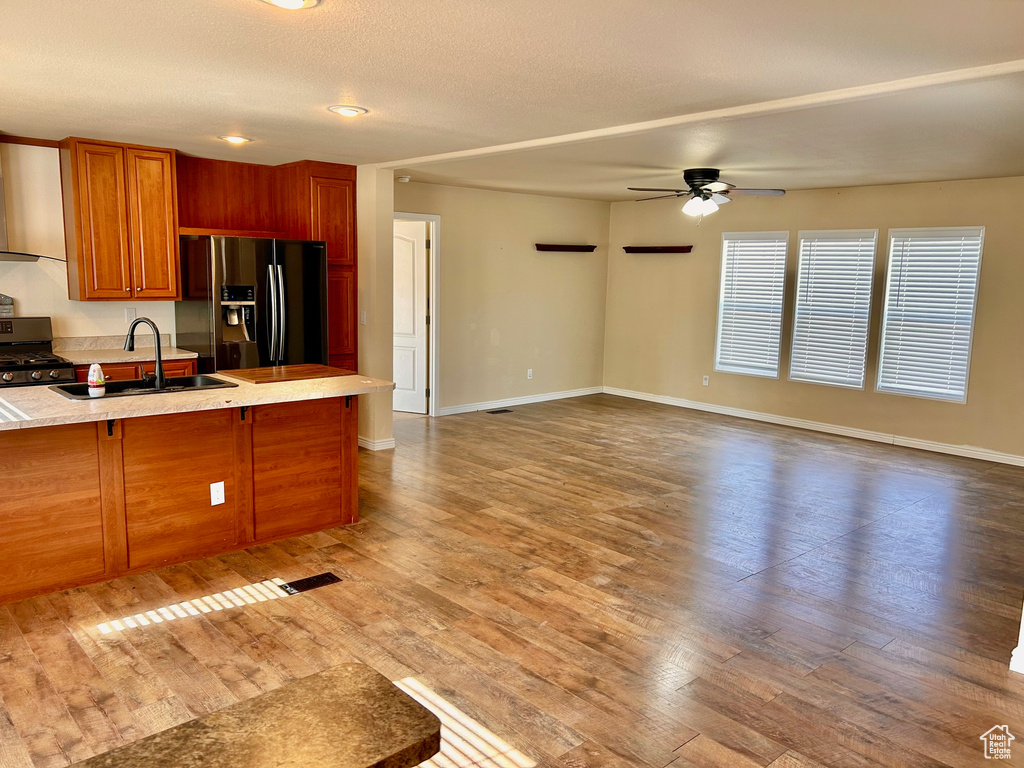 Kitchen featuring refrigerator with ice dispenser, black range with gas cooktop, ceiling fan, hardwood / wood-style flooring, and sink