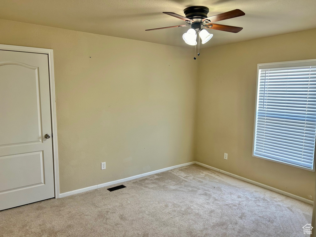 Unfurnished room with ceiling fan and light carpet