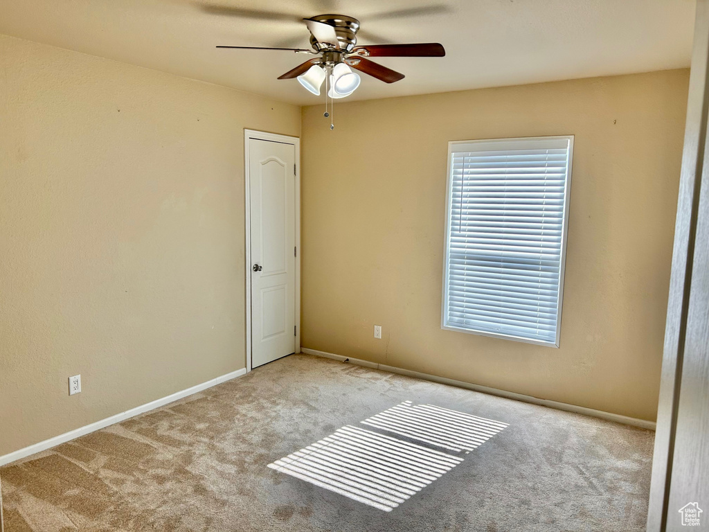 Unfurnished room featuring light carpet and ceiling fan