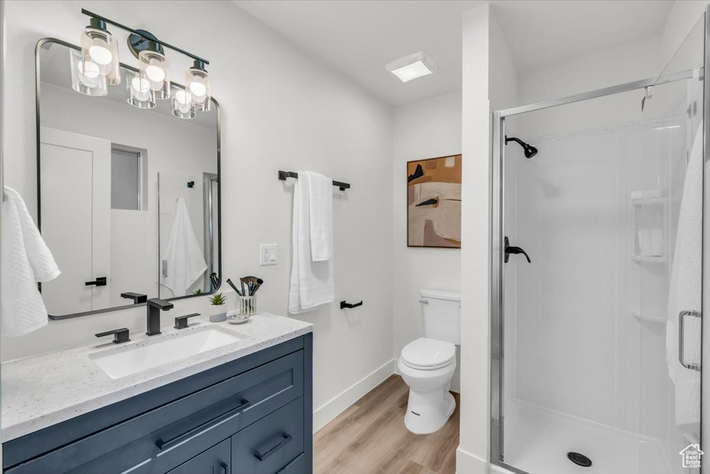 Bathroom featuring hardwood / wood-style floors, vanity, toilet, and a shower with shower door