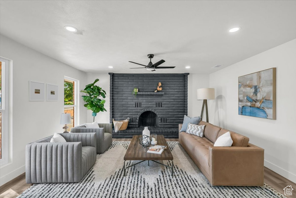 Living room with ceiling fan, a fireplace, and hardwood / wood-style floors