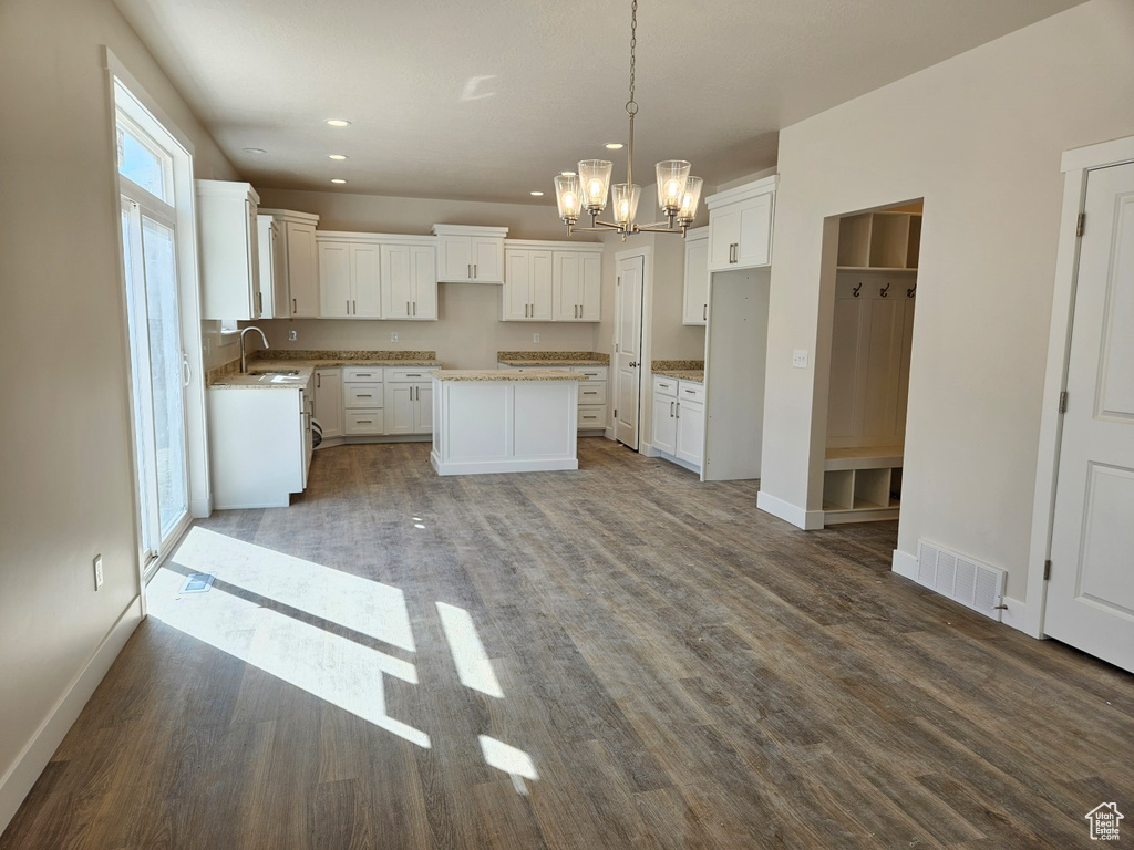 Kitchen featuring white cabinets, pendant lighting, sink, a kitchen island, and wood-type flooring