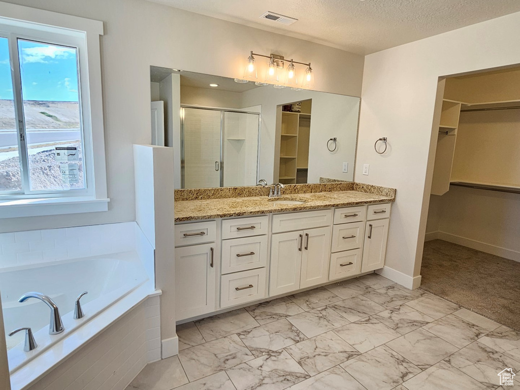 Bathroom with a textured ceiling, independent shower and bath, and vanity